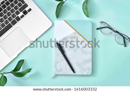 Stylish notebook with laptop and eyeglasses on color background