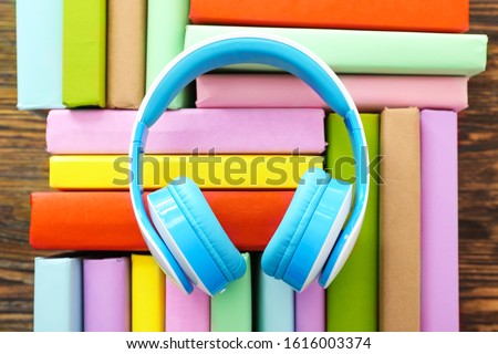Books and modern headphones on wooden background. Concept of audiobook