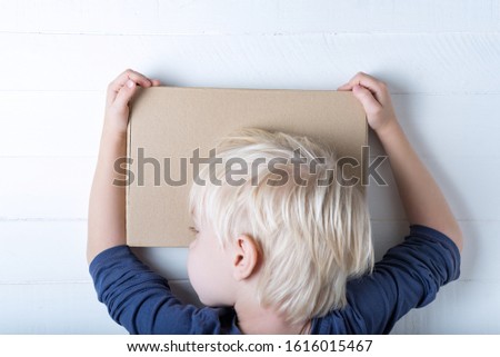 Boy hugging a parcel. Cute child holding a box. White background, top view.