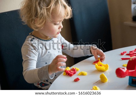 Cute girl playing with many colorful doughs.