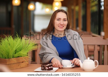 Young girl in cafe sits and drinks tea with dessert
