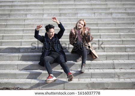 A couple of friends are sitting on the steps in the city

