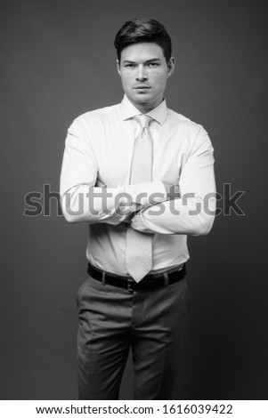 Studio shot of young handsome businessman against gray background