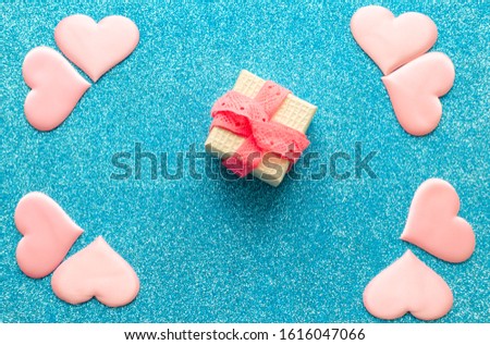 Valentines day pattern background flat lay  pink hearts and a gold gift box with rose ribbon on a glittering classic blue background with copy space. love wedding romantic concept, minimal top view