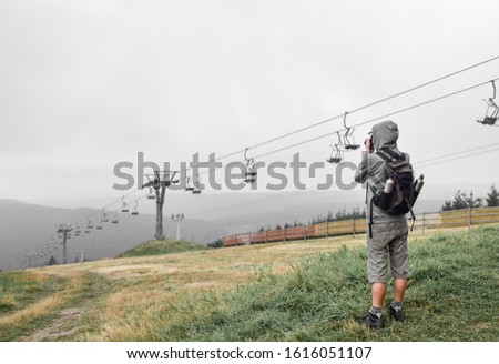 tourist man take a photo of Skilift on the mountain in fog day,people lifestyle