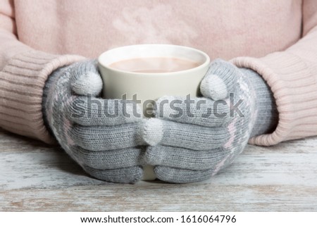 Hands in warm gloves hold a cup with a hot cocoa drink, tea or chocolate. Close-up. Rest during winter sports Royalty-Free Stock Photo #1616064796
