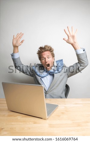 Businessman sitting at his office desk shocked by what he sees on his laptop computer