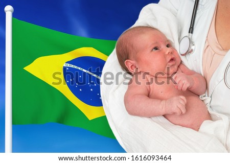Birth rate in Brazil. Newborn baby in hands of doctor on national flag background.