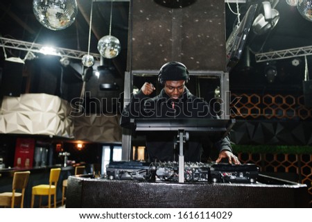 African american dj play music on decks at night club. Royalty-Free Stock Photo #1616114029