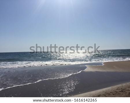 Isolated Sea Beach, Photo. Waves Splashing over sand and rock. Mountain in the background.
