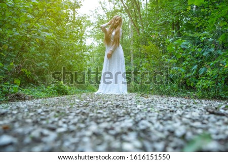 Dark mood photo of a woman while standing and posing in the forest.
