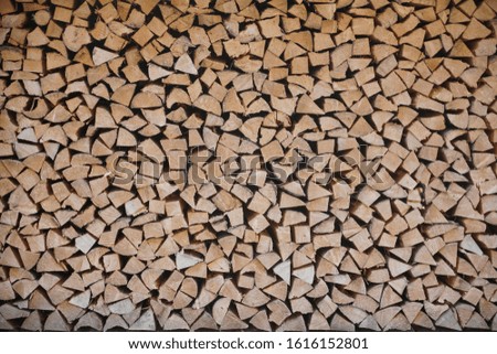 Background of stacked, dry chopped logs used for firewood.