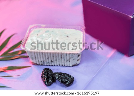 Delicious dessert in plastic package with prunes on table and violet wrapping close up. Food concept