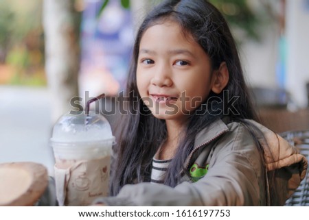 Portrait shot of the little Asian girl drinking chocolate milk and smile with happiness select focus shallow depth of field