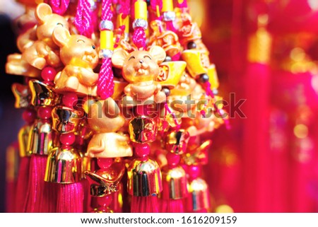 Group of small gold rat with ribbon hanging at Chinese souvenir store for Chinese Lunar New Year in Year of the Rat, selective focus blurred red background, Chinese language mean luck, wealth