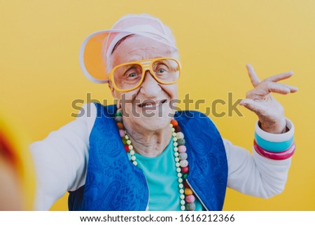 Funny grandmother portraits. 80s style outfit. trapstar taking a selfie on colored backgrounds. Concept about seniority and old people