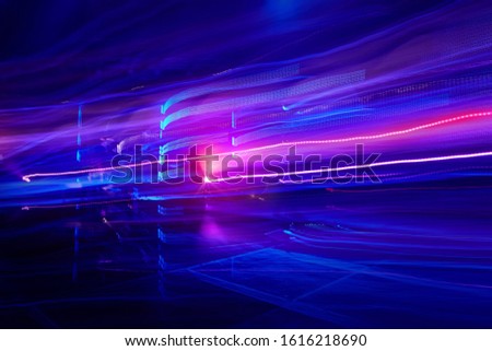 Abstract neon colorful glowing light trails background, motion blur effect. Glowing vibrant blue pink laser lights. Futuristic fluorescent background technology science wallpaper design, copy space
