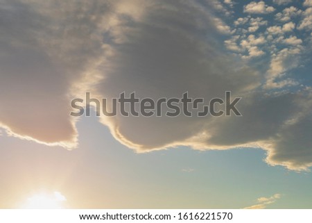 Beautiful cirrus and cumulus clouds on a bright blue sky lit by the sun. Sunset and dusk. Colorful positive natural landscape
