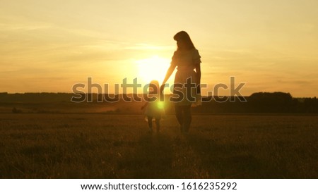 concept of a happy childhood. child mom play in the meadow in the sun. mother and little daughter walking in a field in the sun. Happy young family. concept of happy family.