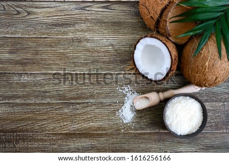 Coconut. Whole coconut, shell, coconut flakes and green leaves on a wooden background. Big nut. Tropical fruit coconut in the shell. SPA. Food photo. Photo background. Texture tropical fruit.