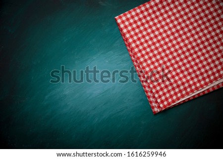 Top view of checkered kitchen tablecloth on concrete background.