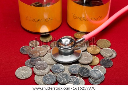 Coins bottle and stethoscope on red background. Concept of financial planning for health care. Selective focus.