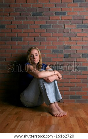 bored looking sad woman sitting with knees up