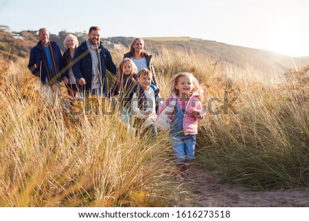 Multi-Generation Family Walking Along Path Through Sand Dunes Together Royalty-Free Stock Photo #1616273518