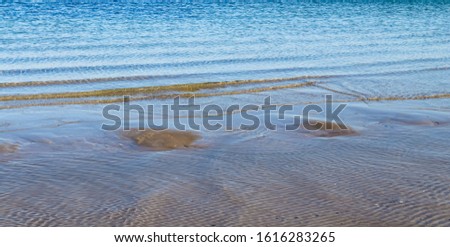 Detailed view on a water surface reflecting the blue sky and some sunlight