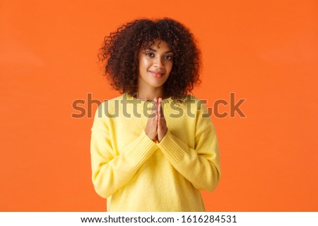 Girl feeling relish is near, something good will happen. Pleased and assertive, confident african-american woman clasp hands and smiling, awaiting, anticipating luck, orange background