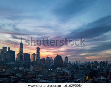 Dusk falls over the downtown Manhattan skyline with the lights of the skyscrapers contrasted against the colorful evening sunset sky in New York City NYC