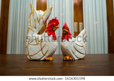 Partial and selective focus image of a pair of white wooden chicken statues with red heads. Photographed from a short distance, suitable for decoration and souvenirs.