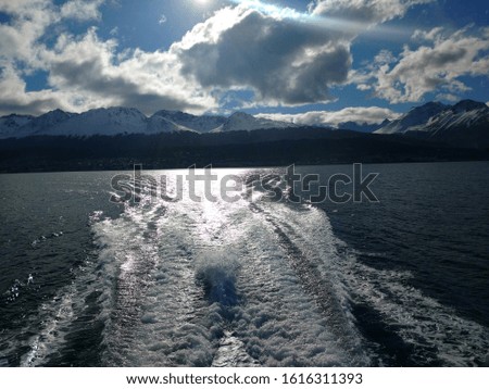 
Beagle Channel at sunset with a trail of the boat engine, with the snowy Andes Mountains in the background