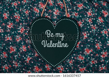 Dark wooden heart with a sign on a flowers pattern background, Valentines day concept