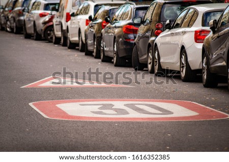 speed limit on a street with cars parking on the side