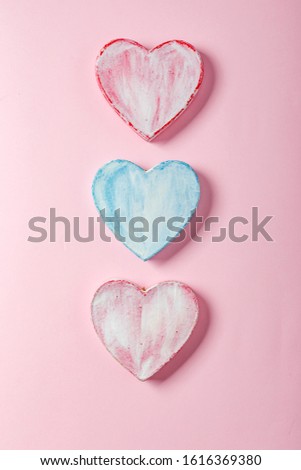 Three valentine hearts made of paper mache on a pink background. Symbol of love and holiday Valentine's Day. Minimalism concept, template for congratulations. Top view, place for text.