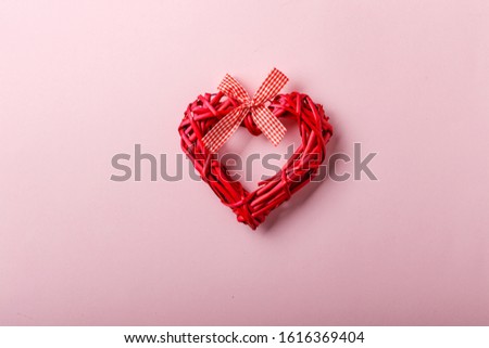 Decorative valentine heart made of twigs on a pink background. Symbol of love and holiday Valentine's Day. Minimalism concept, template for congratulations. Top view, place for text.