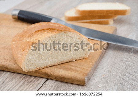 long loaf on a wooden board and knife. Delicious Ukrainian bread. Sliced white bread.
