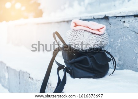 Women's things in the snow on the street in winter. Handbag, scarf, hat. Beauty and fashion.