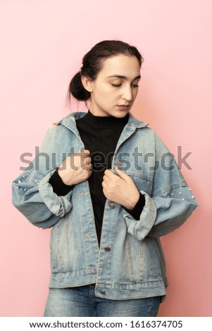Portrait of stylish young female posing against pink background