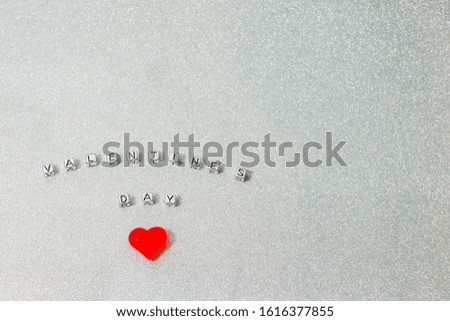 The inscription Valentine's day laid out in small letters on a decorative background with a red heart