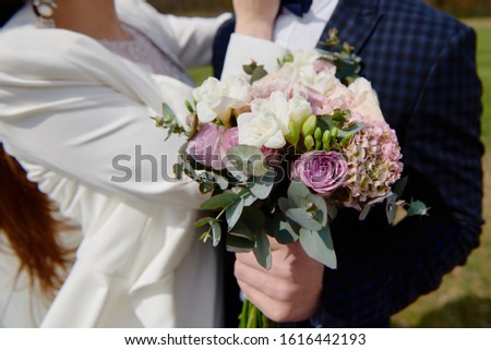 Happy wedding couple hugging outdoors, copy space. Close up of young bride and groom with wedding bouquet