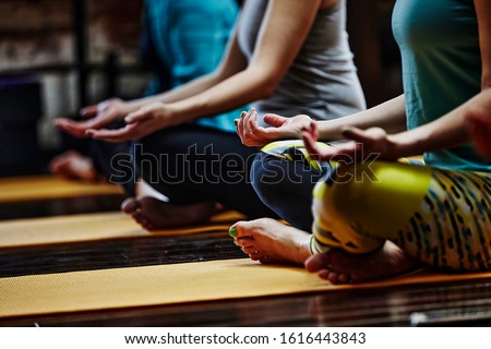 Yoga class people lifestyle with women group in lotus pose meditating in relax silence gym studio indoor.