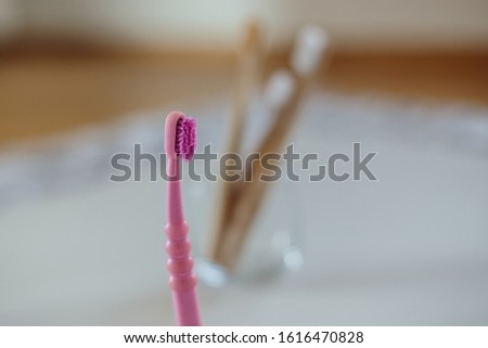 
An old plastic toothbrush in focus in the foreground, in the background in defocus bamboo brushes in a glass. Ecology plastic free. The choice between a plastic toothbrush and a biodegradable bamboo