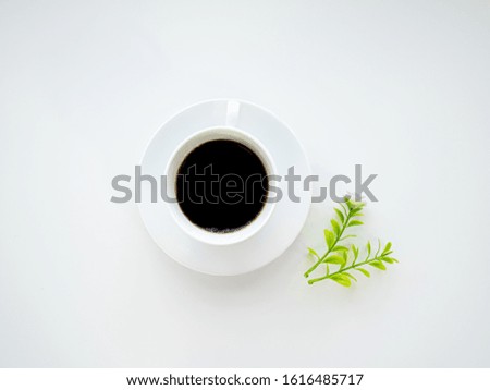 Cup of caffeine black coffee or hot espresso drink beverage in the fresh morning or break time for hard working with violet flower with little green leaves decorated top view on isolated white