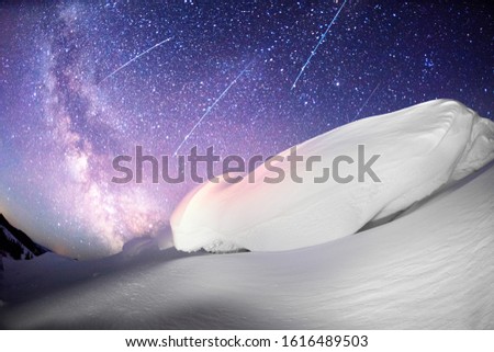 snow cornice at the top is a snow formation formed in the mountains under the influence of wind. Artistic illumination has created a fabulous fiction picture. meteorites and meteors fall