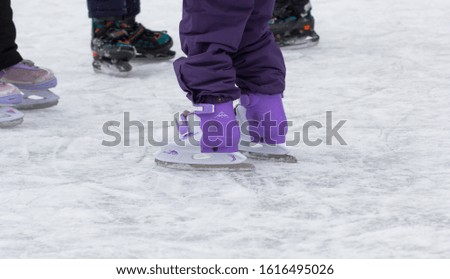Side view of skates on child legs on rink in wintertime