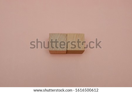 two wooden cubes on a pink background