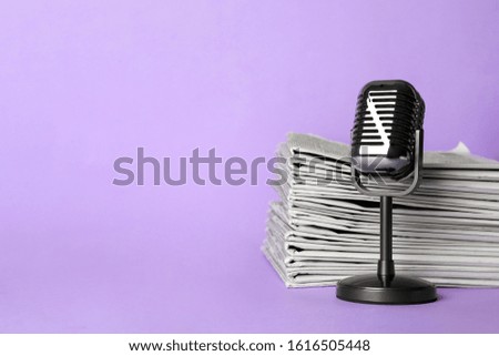 Newspapers and vintage microphone on light violet background, space for text. Journalist's work