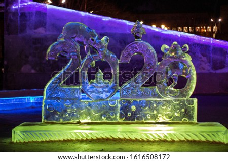 Figures 2020 made of ice, new year. Transparent ice sculpture 2020, glowing yellow at night. Banner, blue design. symbol of the year of the rat. Shallow depth of field, soft focus.